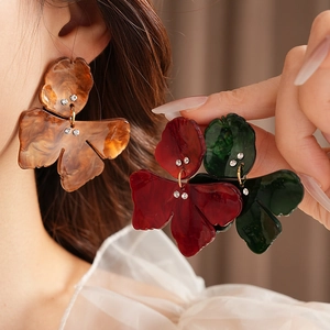 Detail of floral resin earrings with rhinestone accents in brown, red and green shades