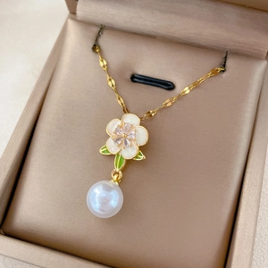 Détail d'un collier fleur dorée avec pétales blancs et perle dans un écrin à bijoux