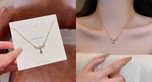 Detail of gold chain necklace with blue teardrop pendant and white zircon accents