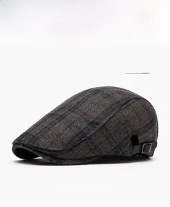 Detail view of grey plaid wool beret cap with leather side strap and metal buckle