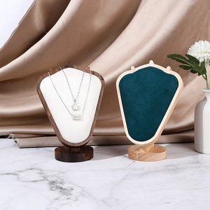 Velvet bust necklace display stand with walnut and light wood base on marble background