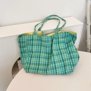 Macro shot of green plaid canvas tote bag showing spacious yellow fabric lining detail
