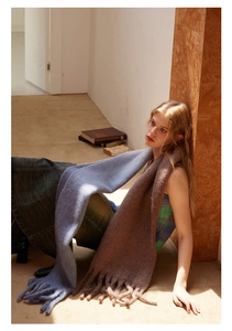 Detail of soft wool blend scarf featuring blue and brown gradient tones with fringe trim