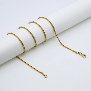 Collier chaîne torsadée en acier inoxydable doré avec fermoir mousqueton sur socle blanc