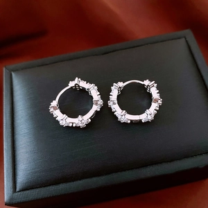 Gros plan de boucles d'oreilles fleurs en argent et zircon sur un écrin noir