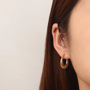 Close-up of dual-tone U-shape hoop earrings with vintage snakeskin texture and gold plating