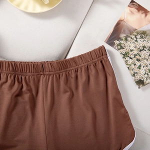 Detailed texture of brown stretch sports shorts with white trim on a neutral background