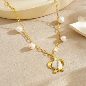 Collier élégant en chaîne dorée avec perles blanches et pendentif tortue sur fond beige