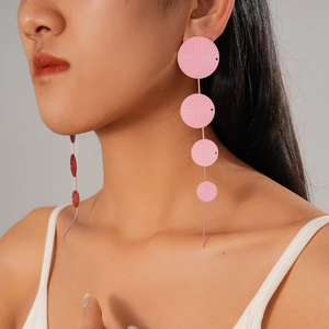 Close-up of pink geometric tiered circle drop earrings worn by a model in a side view