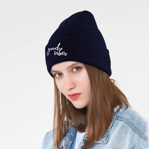 Detail of navy knit beanie showing white good vibes embroidery and fine ribbed texture
