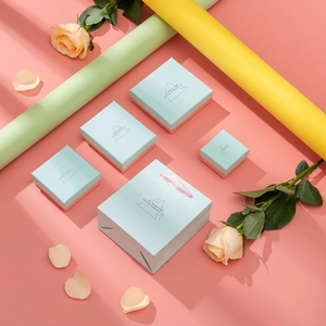 Blue jewelry gift boxes and matching bags with pink ribbons on a floral background