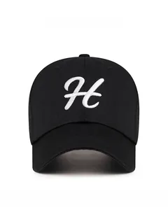 Detailed view of white cursive letter H embroidery on a black cotton baseball cap
