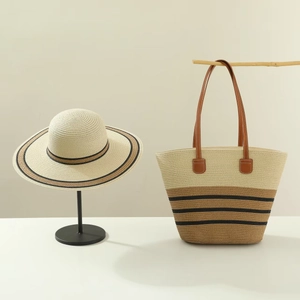Detail of straw sun hat and large tote bag set with black stripes and leather handles