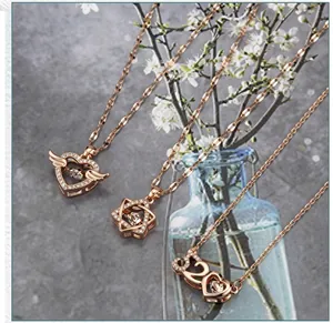 Detail view of heart with wings and star pendants in rose gold with zircon stones