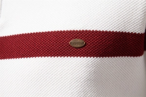 Detail der gestreiften Stricktextur mit ovaler Metallplakette auf einem halben Reißverschluss