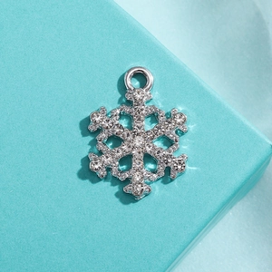 Macro shot of a silver snowflake pendant with sparkling crystals on a blue gift box