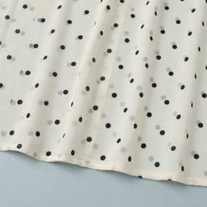 Close-up of black polka dot pattern on ivory chiffon fabric with neat hem stitching