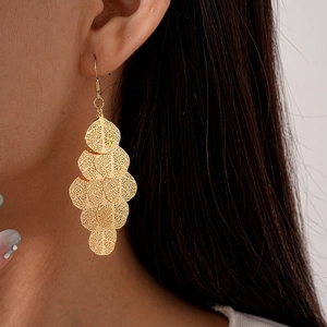 Close-up of golden multi-layer hollow geometric drop earrings worn by a model