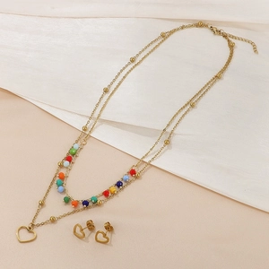 Close-up of golden multi-layer necklace with heart pendant and colorful beads on fabric