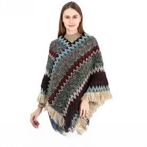Detail of colorful zigzag knit poncho with ethnic pattern and thick fringe trim