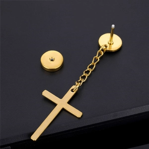 Detailed close-up of gold cross pendant earring with circular stud and fine link chain