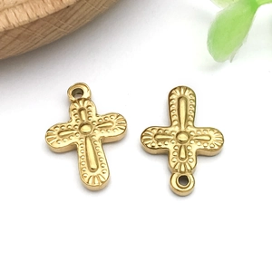 Detail shot of two gold stainless steel cross pendants with vintage embossed patterns