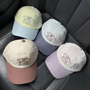 Detail of embroidered cartoon rabbits and lettering on colorful cotton baseball caps