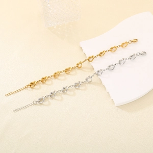 Détail de bracelets nœuds en acier inoxydable or et argent sur fond décoratif épuré