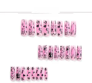 Detail of pink press-on nails with black graffiti stars, moons and heart designs