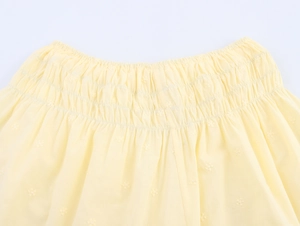 Detail of yellow elastic waistband shorts featuring delicate floral embroidery and poplin fabric
