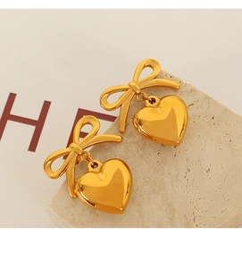 Macro view of gold bow-knot heart pendant earrings featuring a polished metal finish