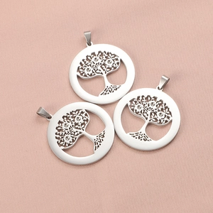 Dettaglio di tre ciondoli Albero della Vita in argento con cristalli su tessuto rosa
