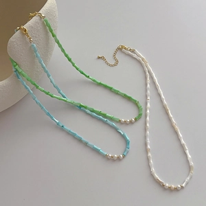 Detailed macro view of three colorful bamboo shell beaded necklaces with natural pearls