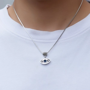 Detail shot of silver evil eye necklace with blue gemstone on model neck