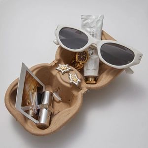 Flat lay of gold star earrings with watch and sunglasses in a pulp tray setup