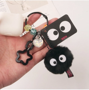 Macro shot of fluffy black pom pom keychain with cartoon eyes and colorful letter beads
