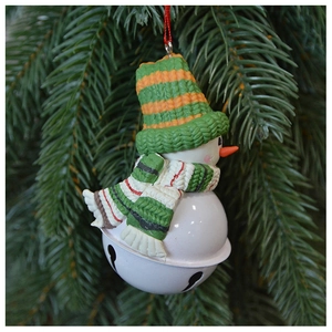 Detail of knitted snowman Christmas bell ornament hanging on green pine branch