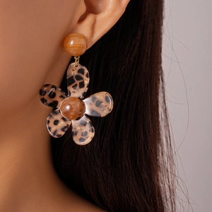 Close-up of model wearing large leopard print resin flower drop earrings with a brown stud