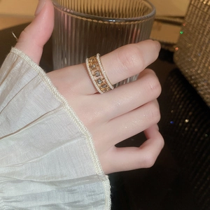 Macro detail of a layered gold ring with square zircons and delicate pearl borders