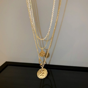 Close-up of vintage triple-layer gold necklace featuring embossed coin pendants