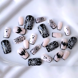 Halloween press-on nails with spider webs, bats, and ghost patterns in pink and black