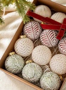 Close-up of assorted 8cm Christmas ball ornaments in a kraft gift box with red ribbon