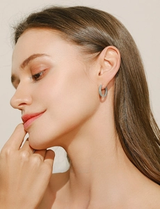 Close-up of silver hoop earring with turquoise and white stones on a model's ear