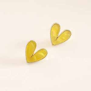 Macro detail of heart-shaped yellow resin earrings with elegant golden beaded borders