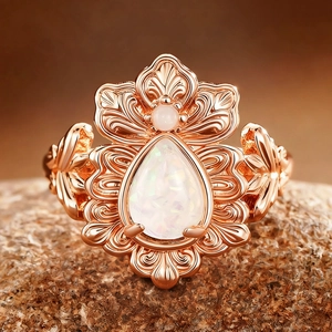 Macro shot of rose gold iris ring with pear-shaped opal and vintage filigree details