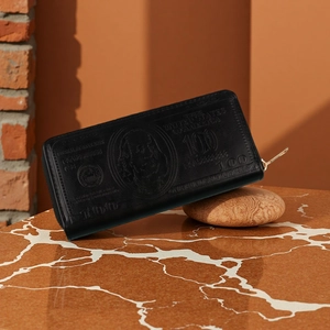 Detail of black long leather wallet with vintage dollar pattern on marble table
