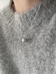 Close-up of elegant grey pearl pendant necklace on a soft grey knit sweater