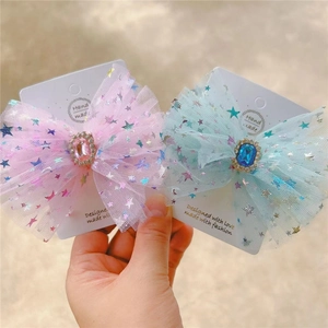 Detail of mesh bow hair clips with colorful star patterns and oval gemstone centers