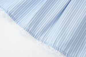 Macro shot of blue striped fabric texture with delicate white lace trim on the garment edge