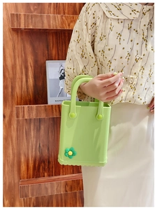 Detail der hellgrünen EVA-Strandtasche mit Sonnenblumen-Anhängern, getragen vor Holzregal